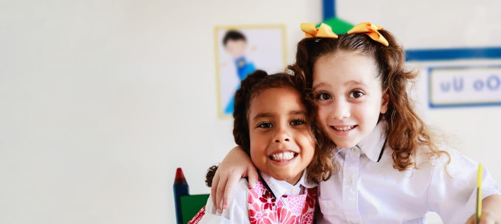 Zwei befreundete Kindergartenkinder lächeln und umarmen sich.