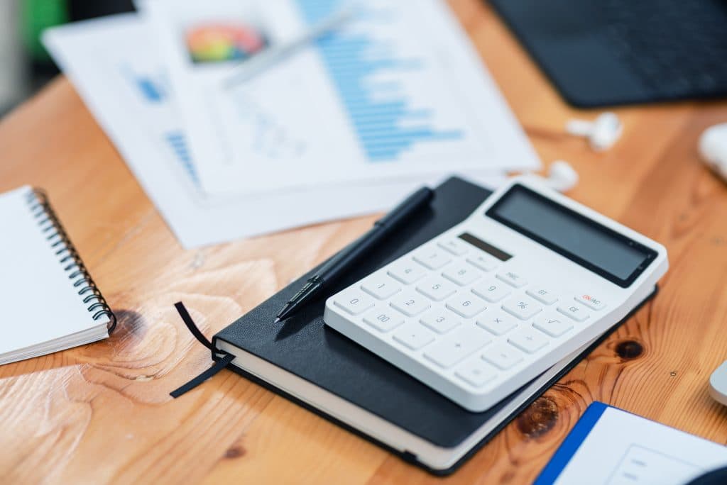 Arbeitsplatz einer Kita-Leitung mit Block, Taschenrechner und Stift.