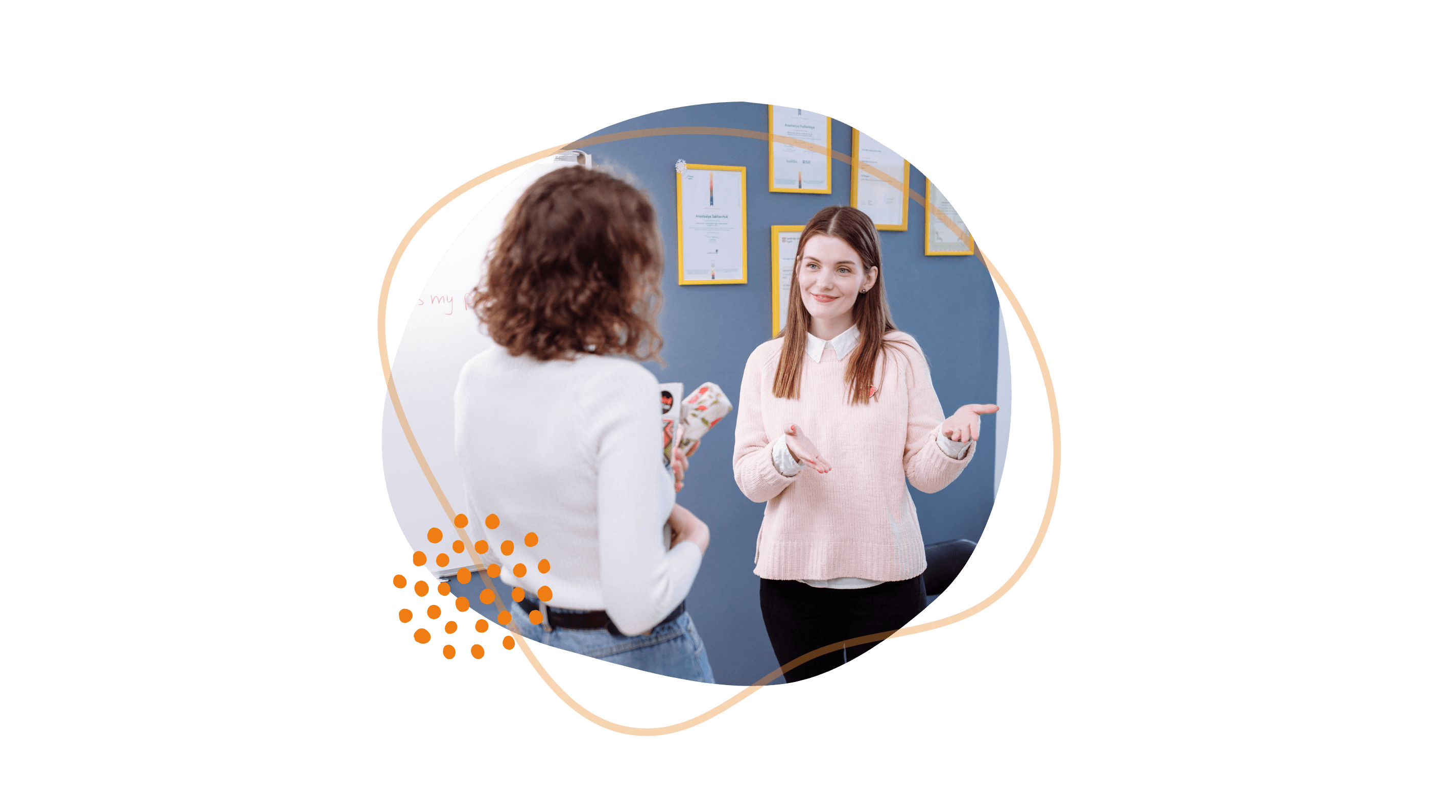 Zwei Frauen unterhalten sich in einem Büro, hinter ihnen hängen gerahmte Urkunden an der Wand.