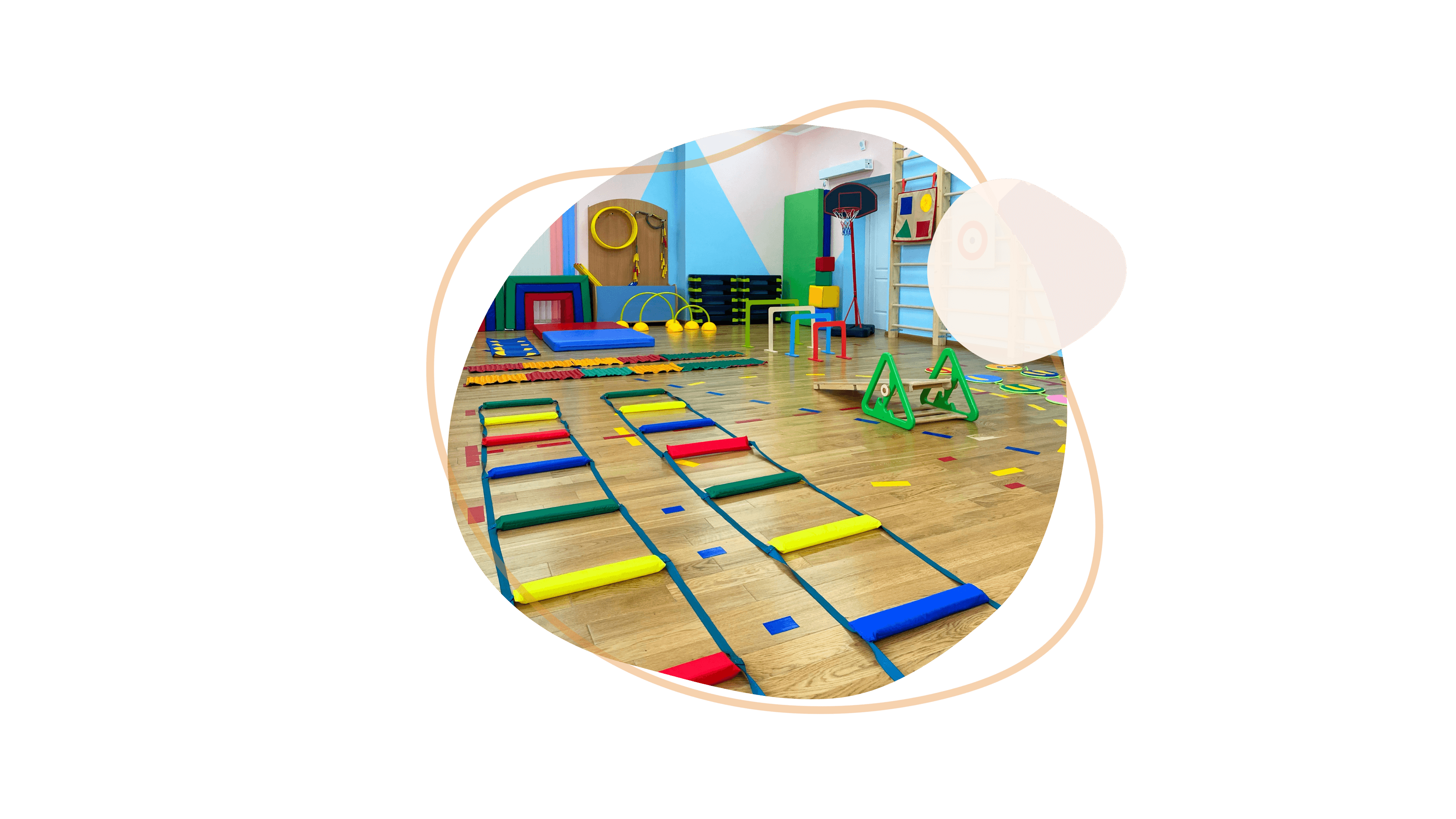 Bewegungsraum im Kindergarten mit buntem Kletter- und Spielmaterial auf einem Turnhallenboden.