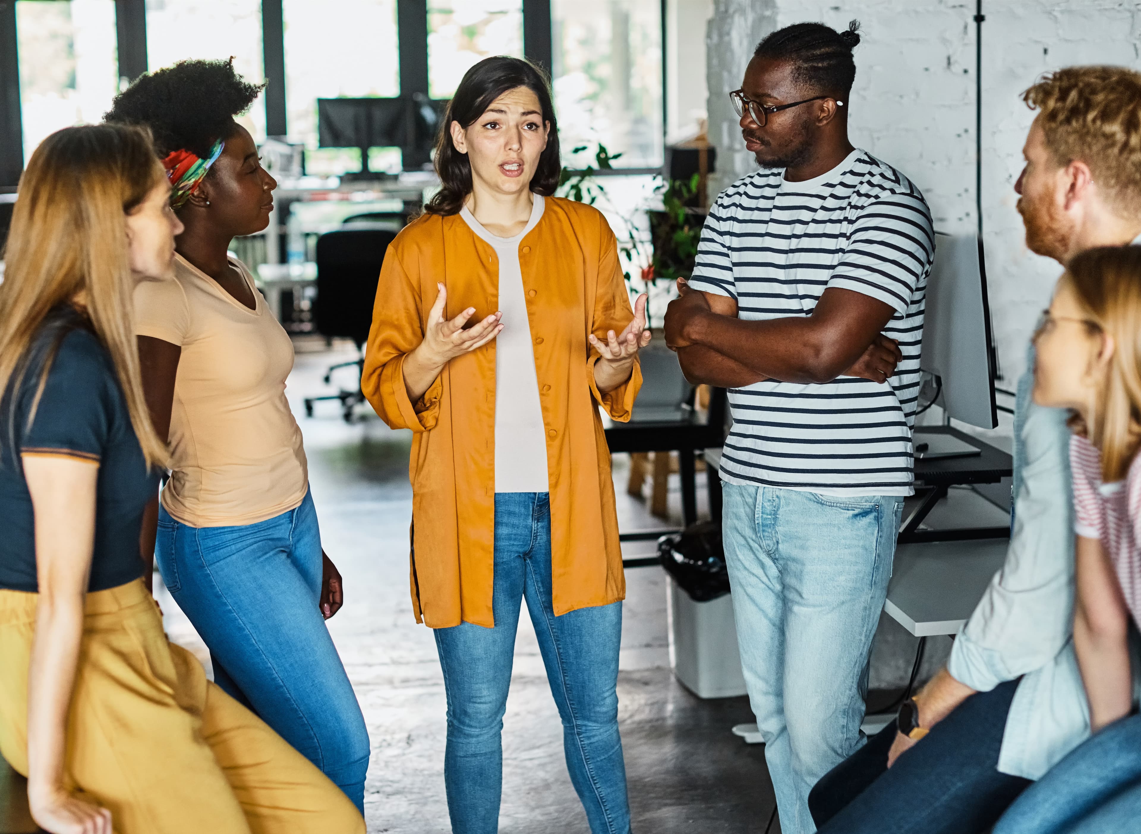 In einem hellen Büroraum ist eine bunt gemischte Gruppe von Erziehern in eine Diskussion vertieft.
