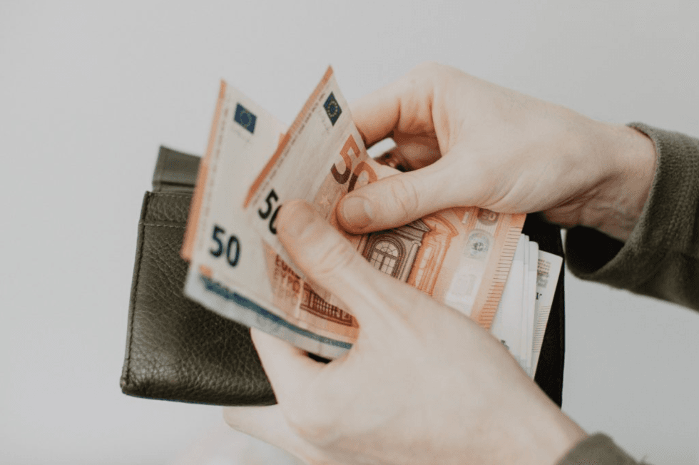 Geldscheine und Portemonnaie in den Händen eines Mannes.