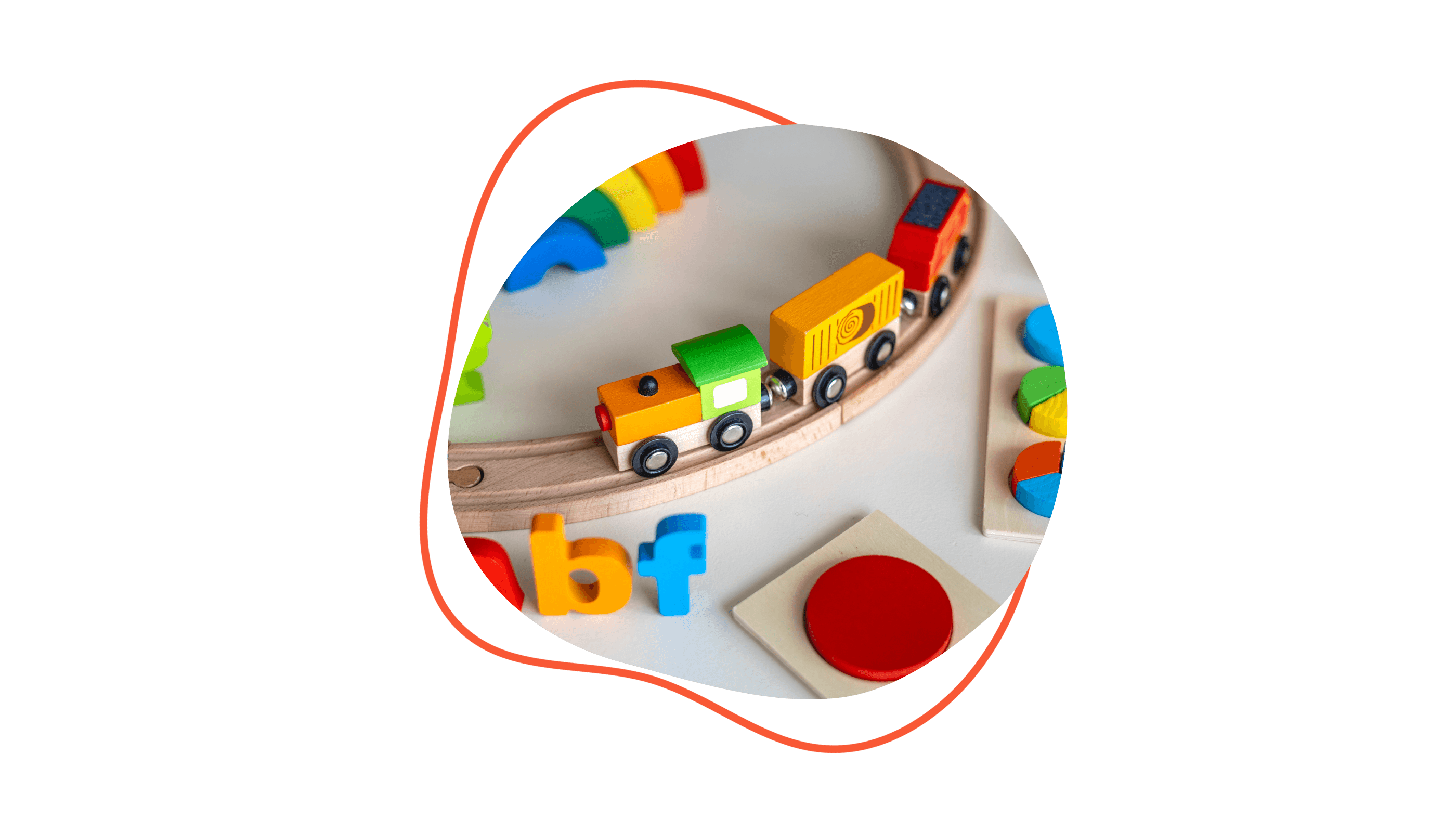 Bunte Holzeisenbahn auf Schienen mit Spielsteinen und Buchstaben auf einem Tisch.